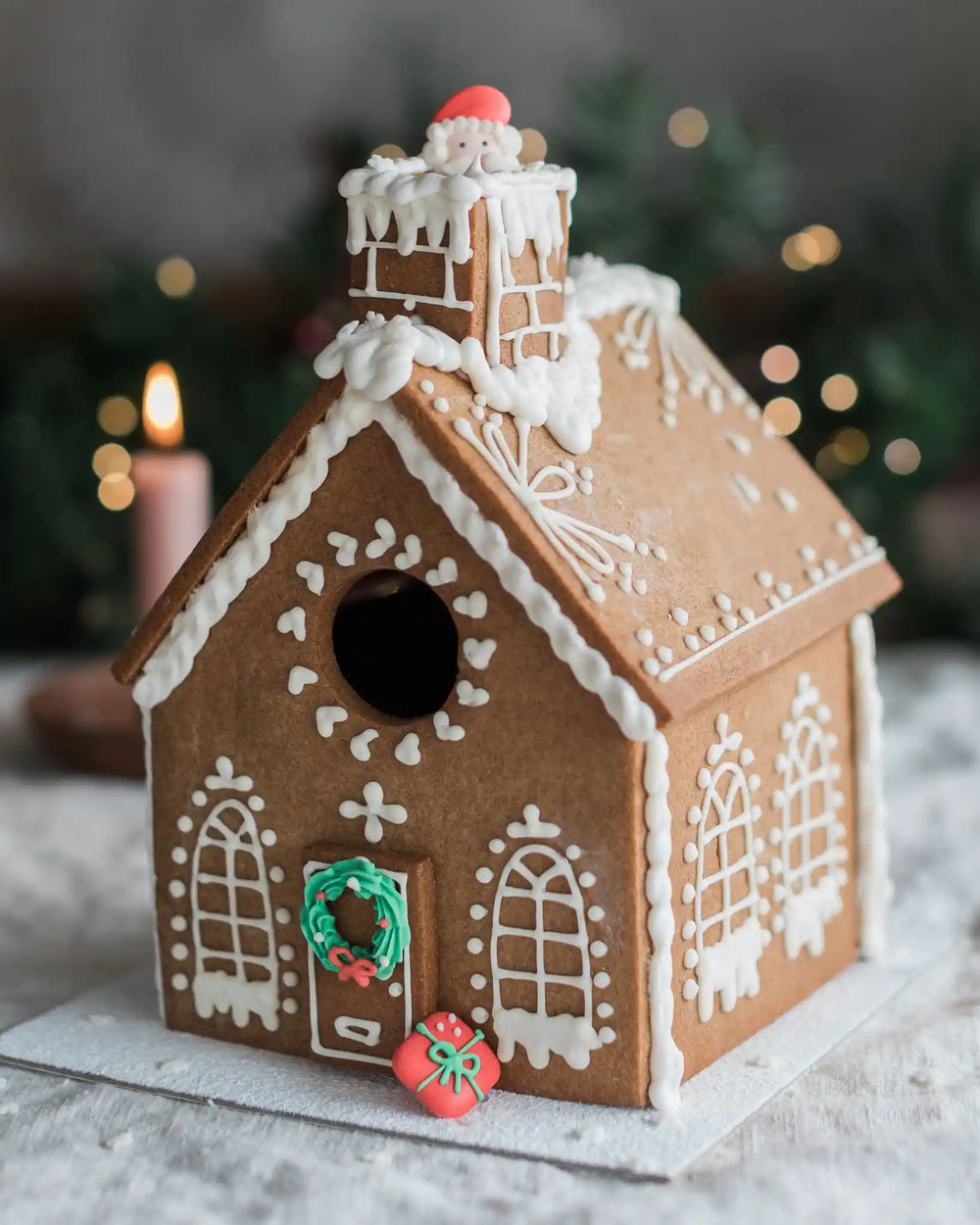 Honeywell Bakes Gingerbread House Baking Kit - A decorated gingerbread house with white icing details, a green wreath on the door, and small red and green sugar decorations