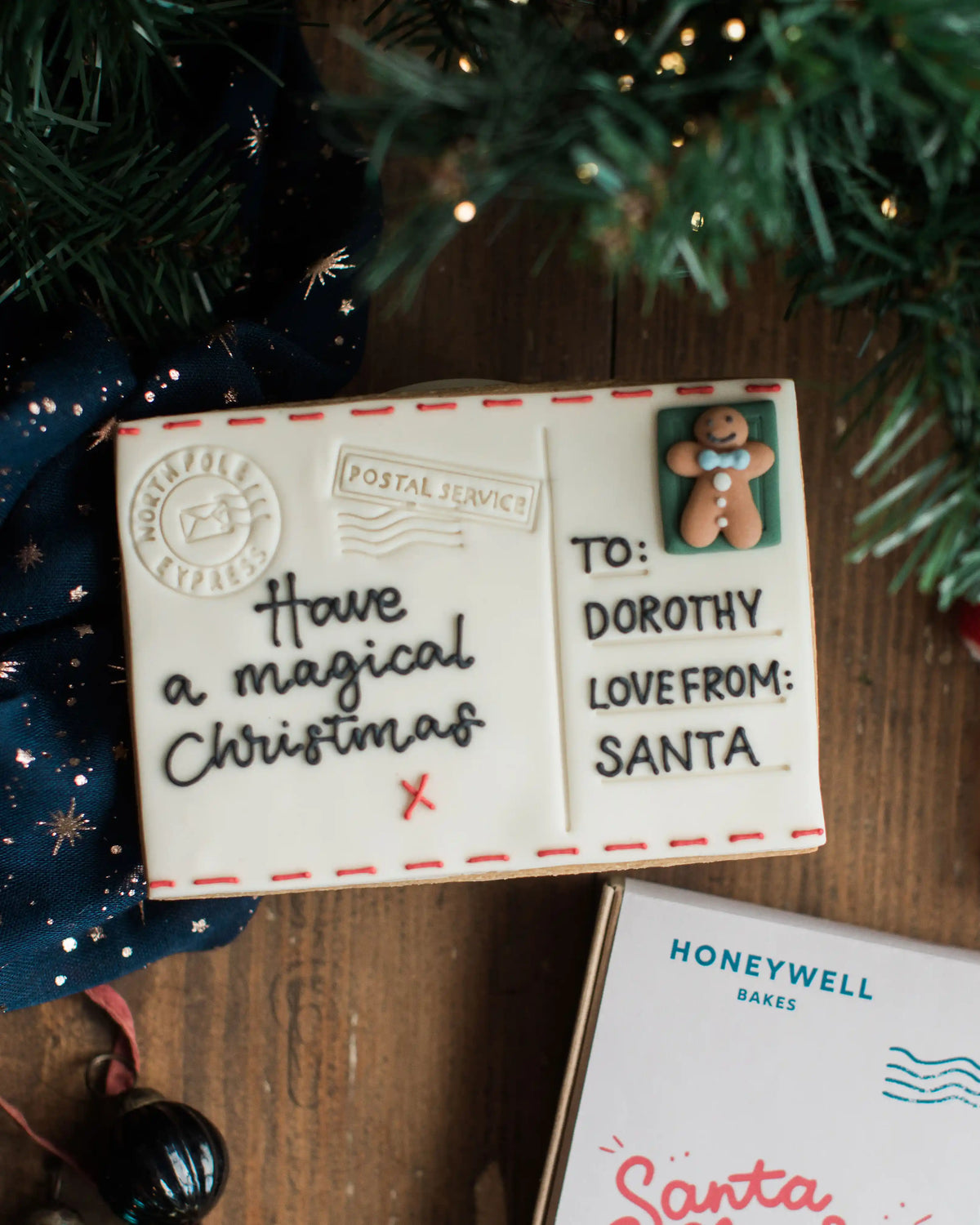 A hand iced Christmas Postcard Biscuit with royal icing piped message in a gift box