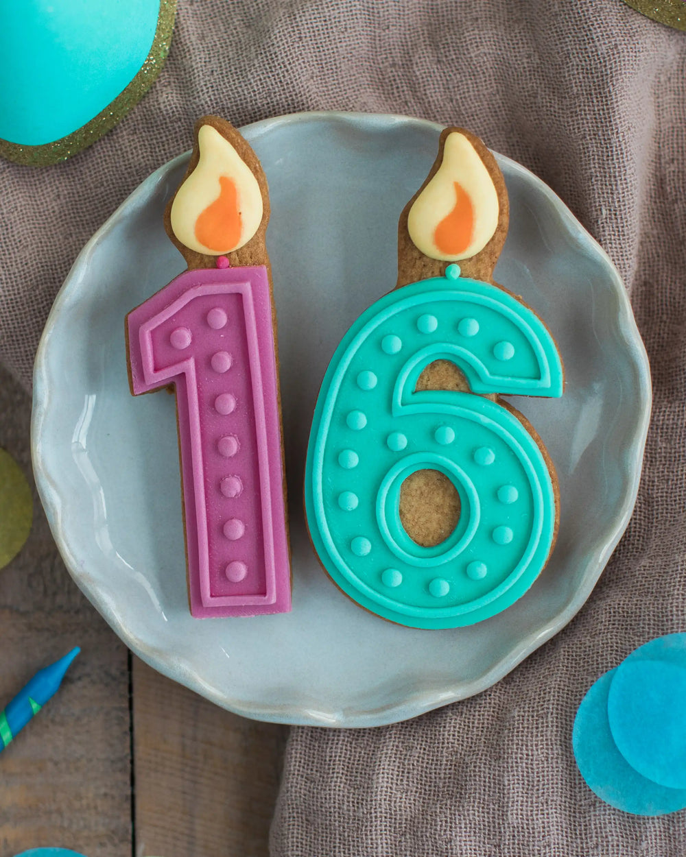 Honeywell Bakes 16th Birthday Biscuits - Two cookie-shaped candles with numbers '1' and '6' on a plate, resembling birthday candles.