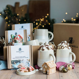 A sustainable festive hamper for two, including hot chocolate, hand iced gingerbread biscuits, stoneware mugs, and mini gingerbread house kits