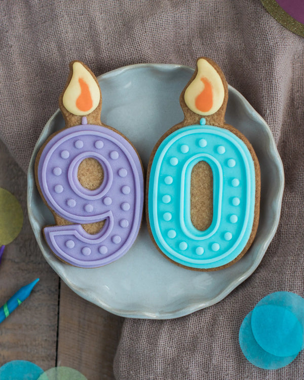 Honeywell Bakes 90th Birthday Biscuits - Two cookies shaped like candles with numbers '9' and '0' on a plate.