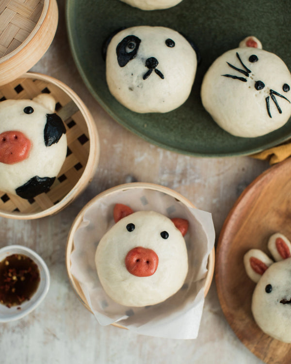 Honeywell Bakes Bao Buddies Baking Kit - Various animal-shaped bao buns on a table with a focus on panda, pig, and rabbit buns.