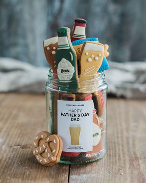 Honeywell Bakes Beer Lover’s Biscuit Jar - Jar of beer themed cookies including bottles and glasses with a label on a wooden surface.