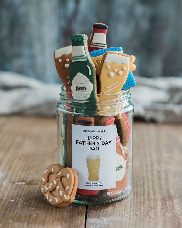 Honeywell Bakes Beer Lover’s Biscuit Jar - Jar of beer themed cookies including bottles and glasses with a label on a wooden surface.