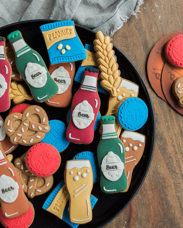 Honeywell Bakes Beer Lover’s Biscuit Jar - Assorted beer-themed cookies on a black plate with a wooden background