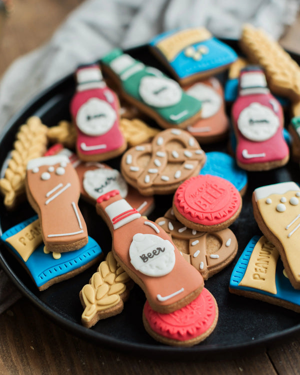 Honeywell Bakes Beer Lover’s Biscuit Jar - Assorted beer-themed cookies on a black plate with a wooden background
