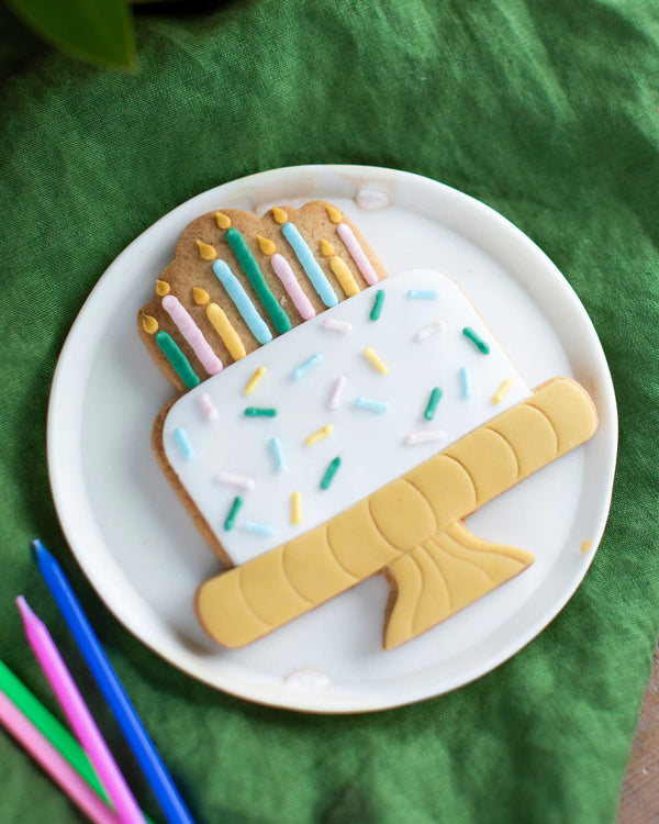 Honeywell Bakes Birthday Cake Biscuit - large hand iced biscuit shaped like a birthday cake with piped candles on a white plate