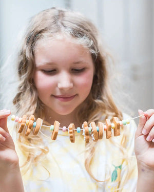Honeywell Bakes Biscuit Jewellery Craft Kit - Young girl playing with a biscuit jewellery on a string