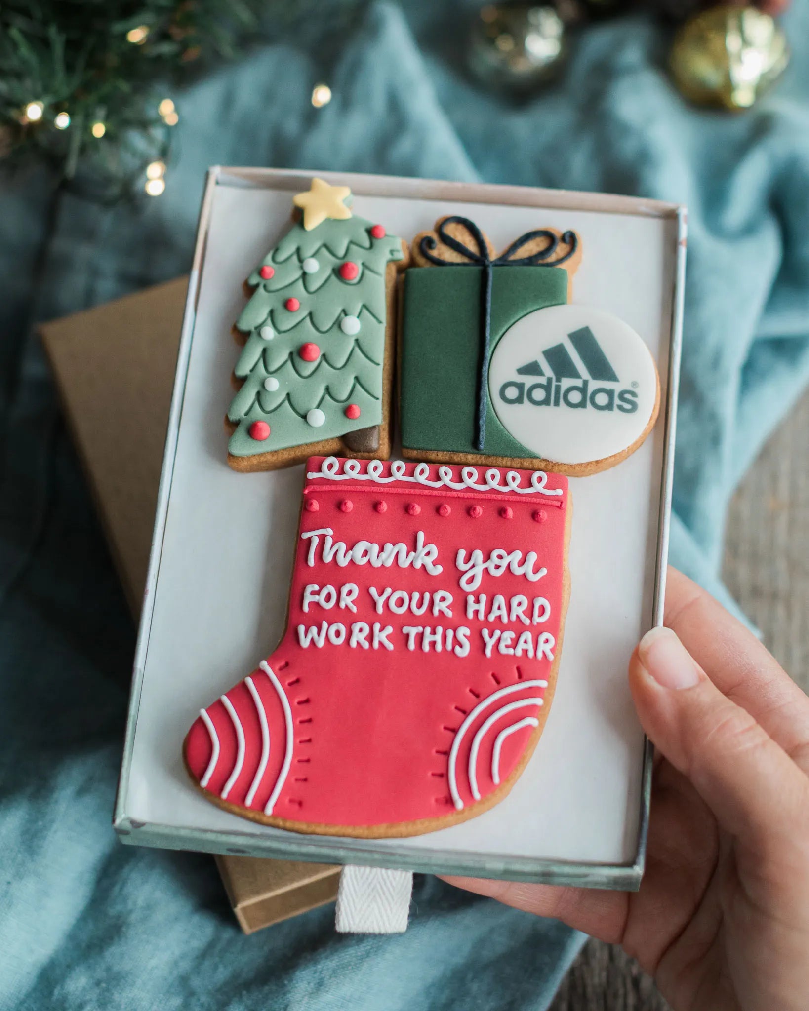 Honeywell Bakes Branded Christmas Employee gift,  decorated festive themed cookies, including a green tree, a gift box, a round white cookie with the Adidas logo, and a red stocking with white text reading 'Thank you FOR YOUR HARD WORK THIS YEAR'. 