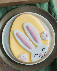Honeywell Bakes Bunny Egg Biscuit - Decorative biscuit shaped like a yellow Easter egg with a bunny face on a white plate.