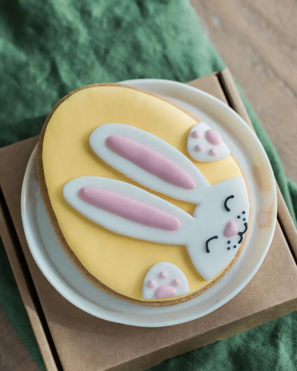 Honeywell Bakes Bunny Egg Biscuit - Decorative biscuit shaped like a yellow Easter egg with a bunny face on a white plate.
