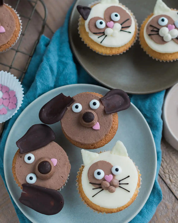Honeywell Bakes Cat & Dog Cupcake Baking Kit - Cupcakes decorated like animals on a plate with a blue cloth background.