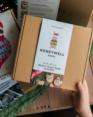 The Children’s Christmas Baking Bundle by Honeywell Bakes, featuring three festive baking kits for kids: Christmas pudding biscuits, Christmas tree brownies and teddy bear cookies, shown in their gift packaging beside a Christmas tree.
