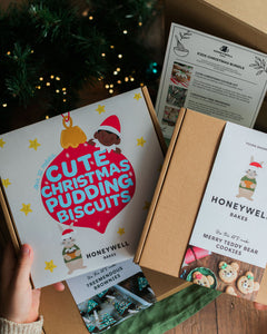 The Children’s Christmas Baking Bundle by Honeywell Bakes, featuring three festive baking kits for kids: Christmas pudding biscuits, Christmas tree brownies and teddy bear cookies, shown in their gift packaging beside a Christmas tree.
