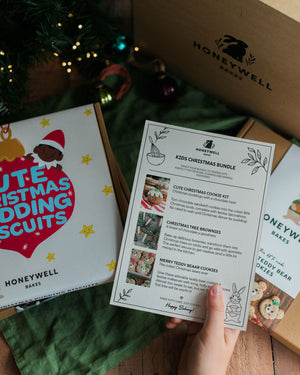 The Children’s Christmas Baking Bundle by Honeywell Bakes, featuring three festive baking kits for kids: Christmas pudding biscuits, Christmas tree brownies and teddy bear cookies, shown in their gift packaging beside a Christmas tree.