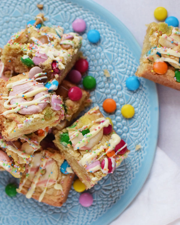 Honeywell Bakes Chocolate Rainbow Blondie Baking Kit  - colourful blondie bars with smarties and party rings on a blue plate 