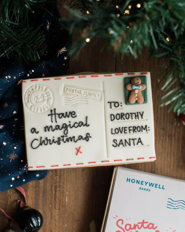 A hand iced Christmas Postcard Biscuit with royal icing piped message in a gift box