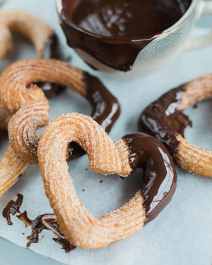 Honeywell Bakes Churros Kit For Baking -  Churros being dipped into chocolate sauce on a light blue surface