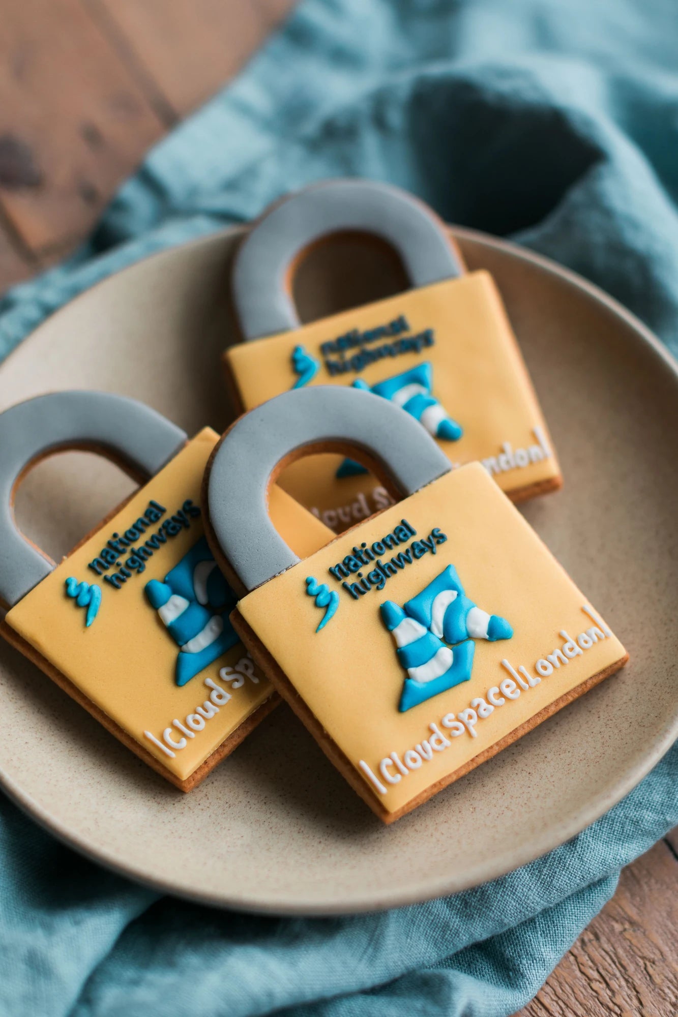 Honeywell Bakes three hand iced padlock shaped cookies featuring the National Highways logo in blue and white 