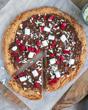 Honeywell Bakes Cookie Dough Pizza Baking Kit - Large cookie pizza with chocolate, raspberries, and marshmallows on a wooden board.