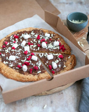 Honeywell Bakes Cookie Dough Pizza Baking Kit - Chocolate pizza with marshmallows and raspberries in a cardboard box on a wooden surface.