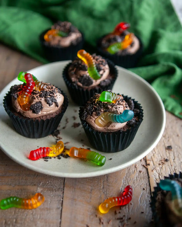 Honeywell Bakes Creepy Crawly Cupcake Baking Kit - Chocolate cupcakes with colourful gummy worms on a white plate, green cloth in the background