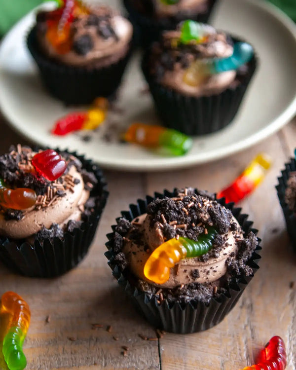 Honeywell Bakes Creepy Crawly Cupcake Baking Kit - Chocolate cupcakes with gummy worms on a wooden surface and plate.