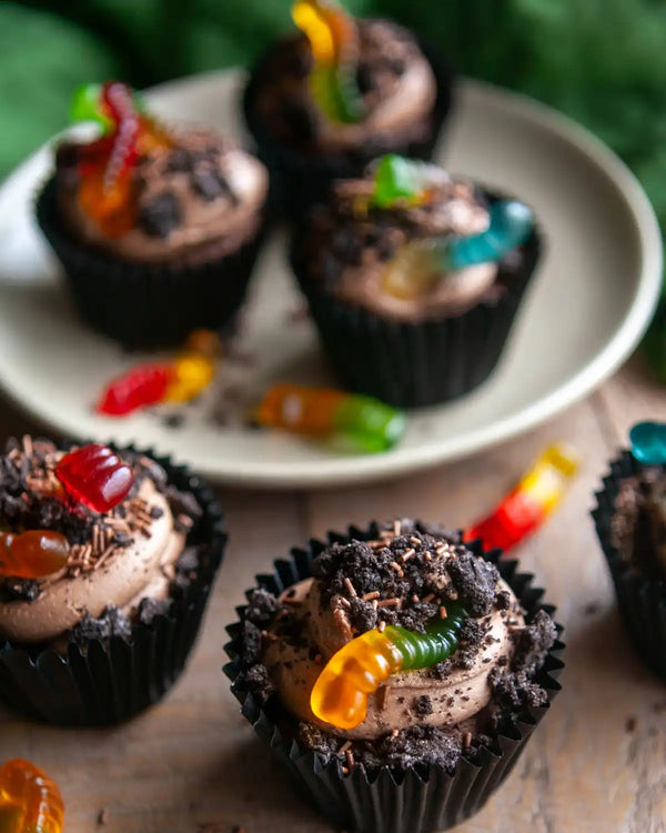 Honeywell Bakes Creepy Crawly Cupcake Baking Kit - Chocolate cupcakes with gummy worms on a plate and surface.