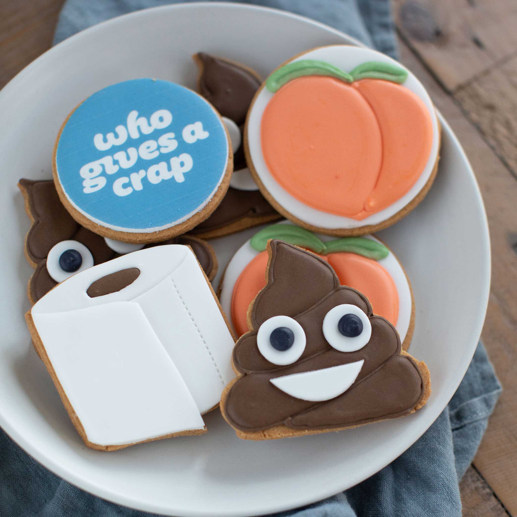 Custom branded biscuits in the shape of toilet roll, peach and poo emoji with Who Gives A Crap logo