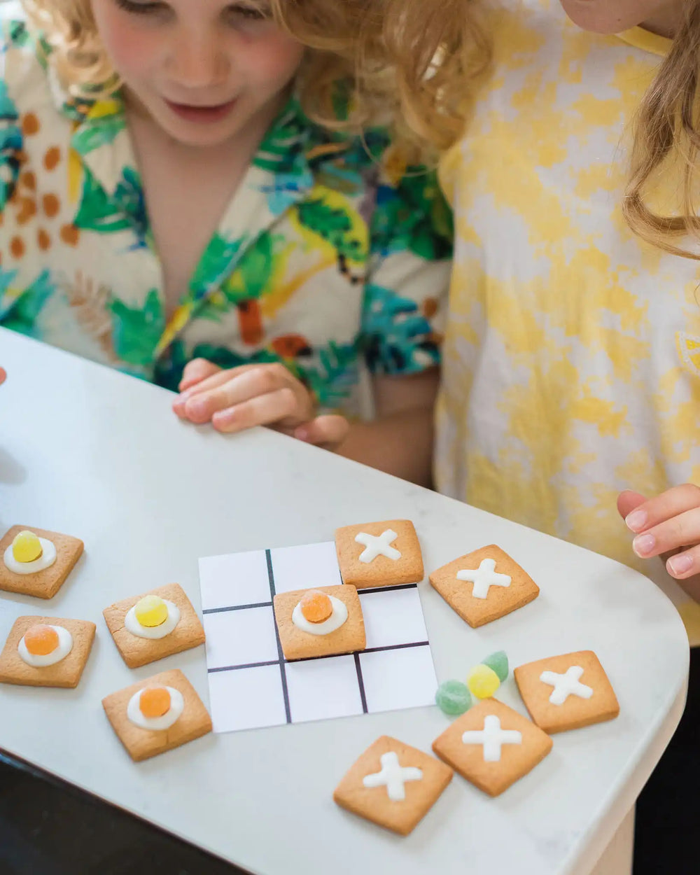 Honeywell Bakes DIY Noughts and Crosses Biscuit Game - vanilla cookies shaped like a game board with decorative elements on a wooden surface.