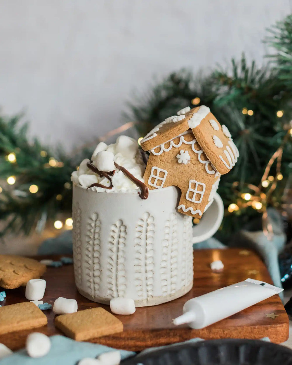 Honeywell Bakes DIY Tiny Gingerbread House Kit - biscuit gingerbread house on a wooden plate with icing tube and biscuits