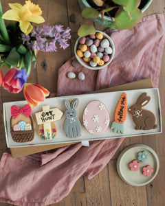 Honeywell Bakes Easter Egg Hunt Biscuit Gift - Easter-themed cookies in a box on a wooden table with flowers and candies.