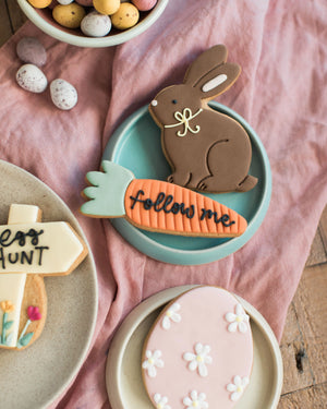 Honeywell Bakes Easter Egg Hunt Biscuit Gift - Easter-themed cookies including a rabbit, carrot, and cross on a pink cloth background.