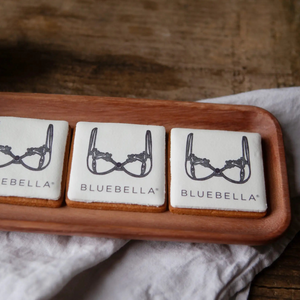 Three cookies finished with edible ink printed branding, with 'BLUEBELLA' logo branding on a wooden board.