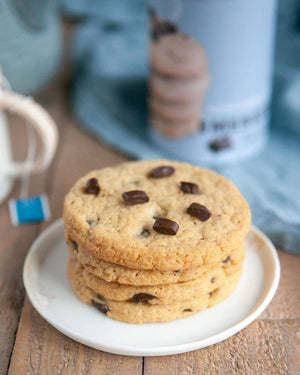 Honeywell Bakes Emergency Tea & Cookies Kit - Stack of chocolate chip cookies on a white plate with a blurred emergency biscuit can in the background.