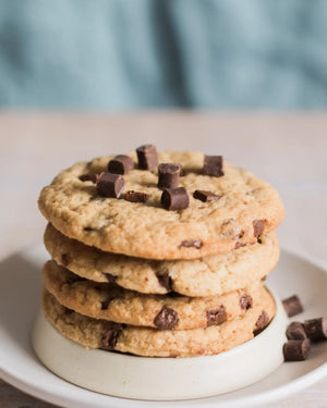 Honeywell Bakes Emergency Tea & Cookies Kit - Stack of chocolate chip cookies on a white plate with a blurred background