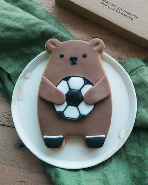 Honeywell Bakes Football Biscuit Bear - Cookie shaped like a bear holding a football on a white plate with a green cloth in the background.