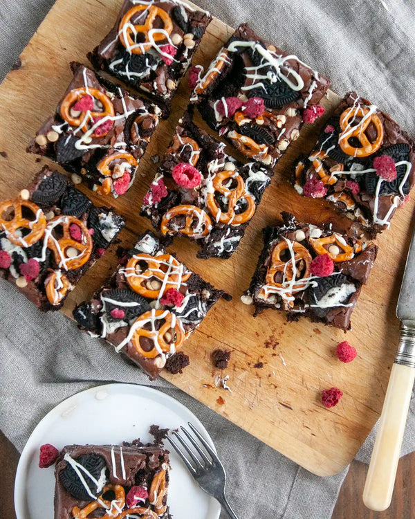 Honeywell Bakes Fully Loaded Brownie Baking Kit - Chocolate brownies with pretzels and raspberries on a wooden cutting board.
