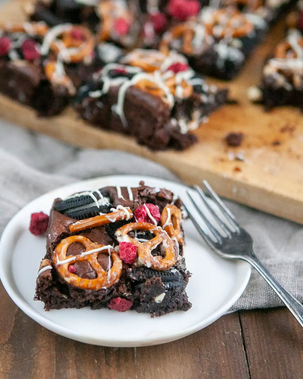 Honeywell Bakes Fully Loaded Brownie Baking Kit - Chocolate brownies with pretzels and raspberries on a wooden cutting board.