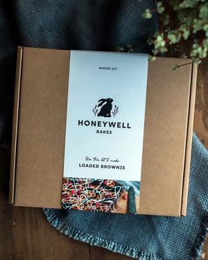 Honeywell Bakes Fully Loaded Brownie Baking Kit - packaging on a wooden surface with a plant in the background