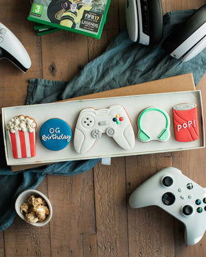 Honeywell Bakes Gamers Biscuit Gift Set - Gaming-themed cookies in a box with controllers and pop corn on a wooden surface