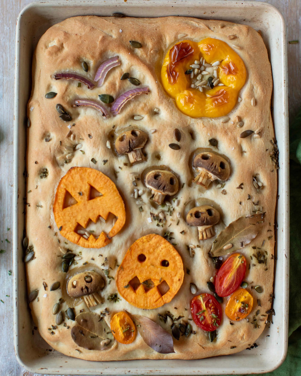 Honeywell Bakes Garden Focaccia Bread Baking Kit - Halloween-themed focaccia bread with vegetables shaped like pumpkins, ghosts, and skeletons on a baking tray.