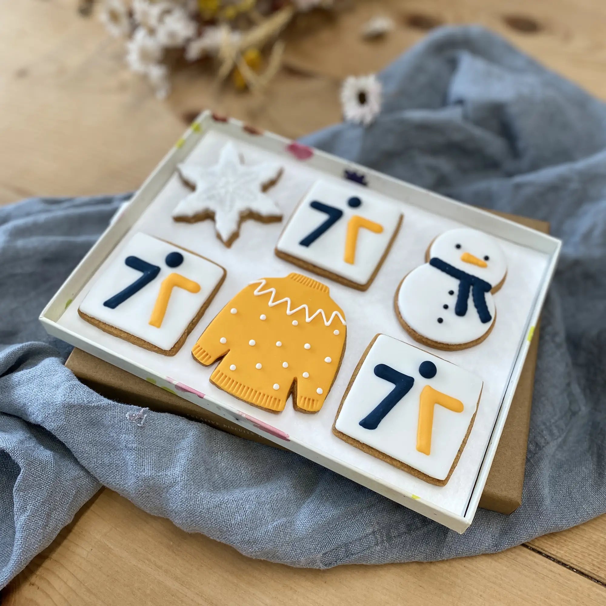 Honeywell Bakes branded biscuit gift box, A boxed set of six hand iced sugar cookies arranged in a gift box. The cookies include a snowflake, a Christmas jumper, a snowman and logo biscuits in brand colours.