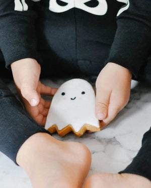 Honeywell Bakes Halloween Biscuit Gift Set - Child holding a small ghost biscuit on a marble surface