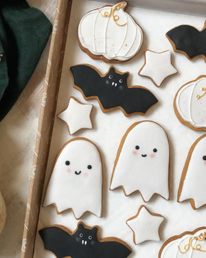 Honeywell Bakes Halloween Biscuit Gift Set - Halloween-themed cookies including ghosts, bats, and pumpkins on a white surface.