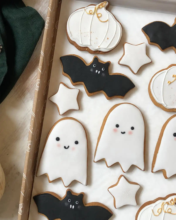 Honeywell Bakes Halloween Biscuit Gift Set - Halloween-themed cookies including ghosts, bats, and pumpkins on a white surface.