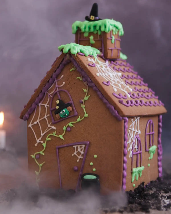 Honeywell Bakes Haunted Gingerbread House Baking Kit - Halloween-themed gingerbread house with purple accents and a witch on a broomstick on top.