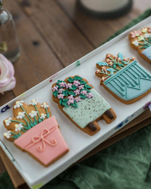 Honeywell Bakes House Plant Biscuit Gift Set - Decorative cookies shaped like potted plants on a white tray with a wooden surface in the background.