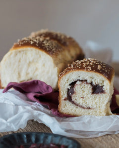 Honeywell Bakes Japanese Milk Bread Baking Kit  - Loaf of bread with sesame seeds and a slice on a purple cloth