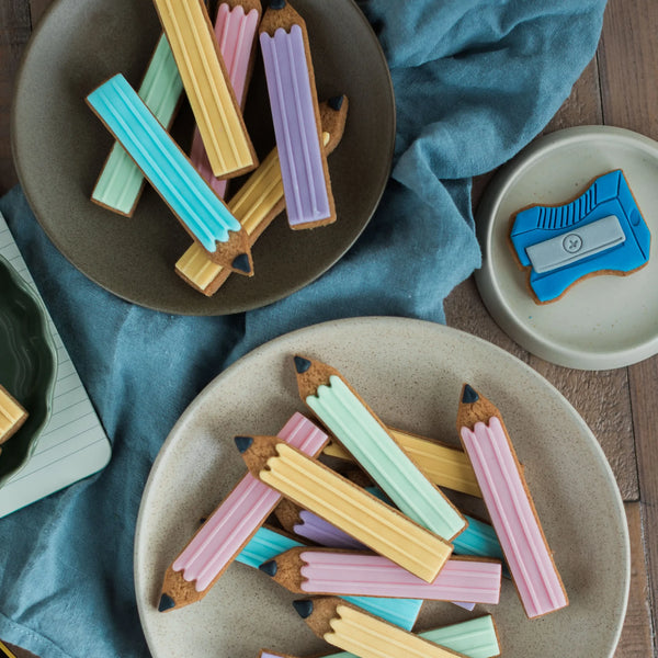 Honeywell Bakes Jar-of-Biscuit-Pencils Colourful pencil-shaped cookies on plates with a blue napkin underneath.